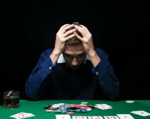 man at poker table head in hands