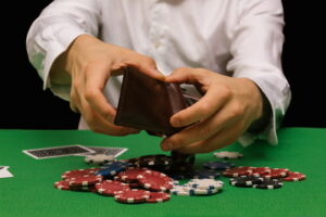 man empties wallet onto poker table debt gambling