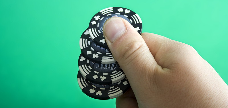 man holding casino chips ante bet poker