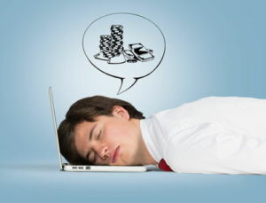 man sleeping on laptop with dream bubble showing chips and money